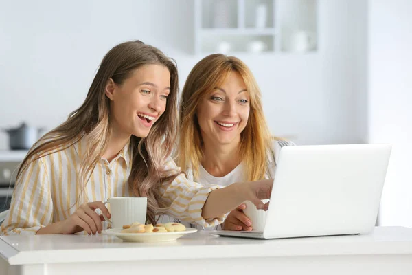 Gelukkig moeder en dochter met laptop in keuken — Stockfoto