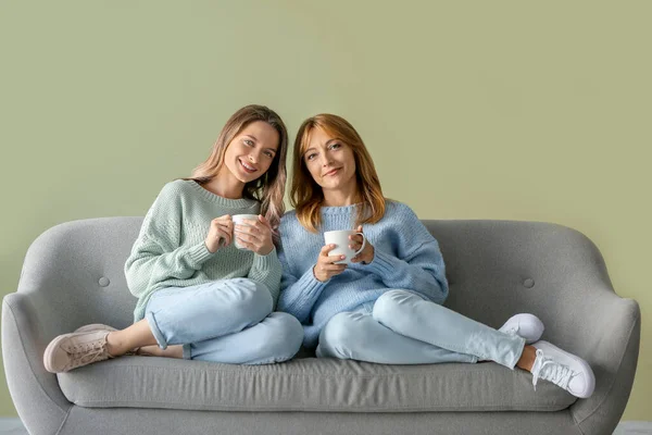 幸せなお母さんと娘はお茶を飲みながら家でソファに座って — ストック写真