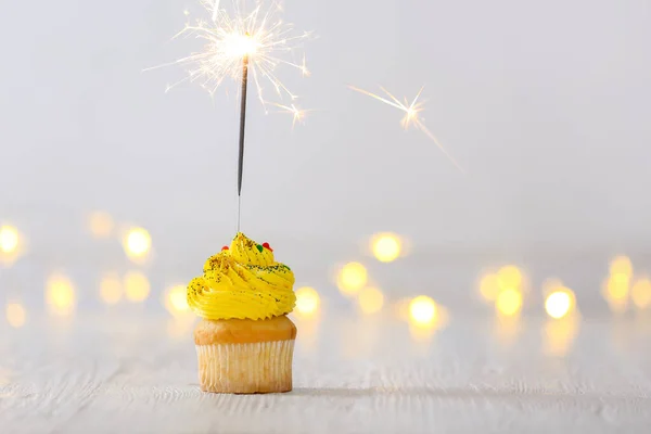 Gustoso cupcake con sparkler su tavolo bianco con luci sfocate — Foto Stock