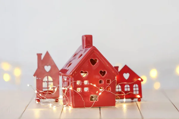 Small houses with glowing garland on white table — Stock Photo, Image