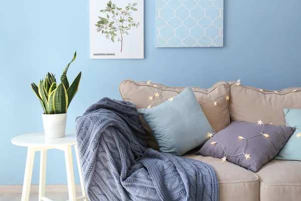 Weiches Sofa mit glühender Girlande im Inneren des Zimmers — Stockfoto