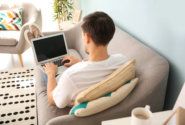 Bonito homem com laptop descansando em casa — Fotografia de Stock