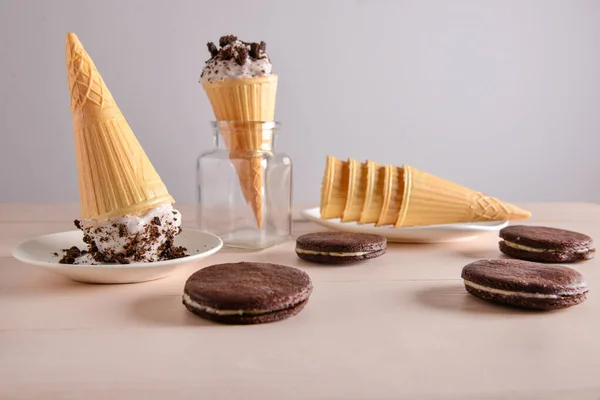Cônes de gaufrettes avec crème glacée savoureuse et biscuits au chocolat sur la table — Photo