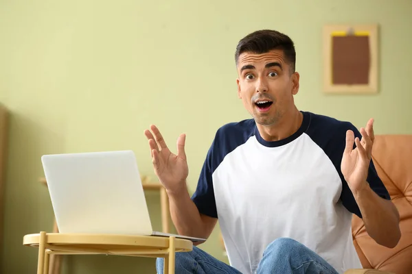 Geschokte jongeman met laptop thuis — Stockfoto