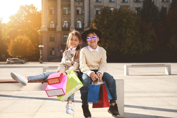 Retrato de lindos niños de moda con bolsas de compras al aire libre —  Fotos de Stock