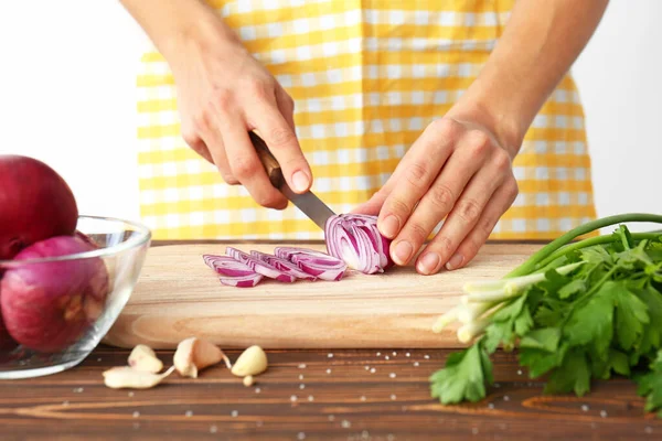 Woman cutting onion in kitchen — Stock Photo, Image