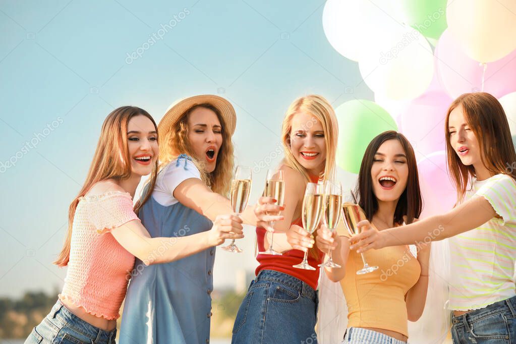 Beautiful young women drinking champagne at hen party outdoors