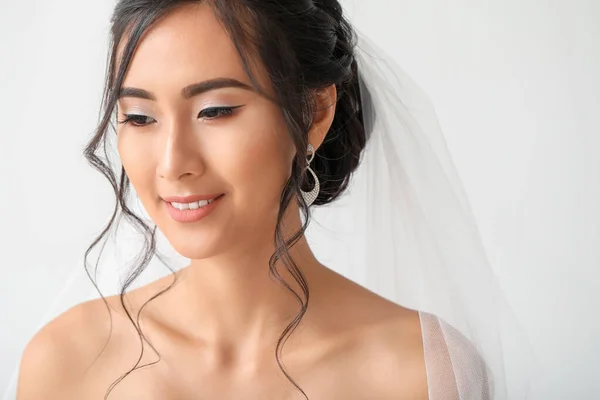 Beautiful young Asian bride on light background — Stock Photo, Image