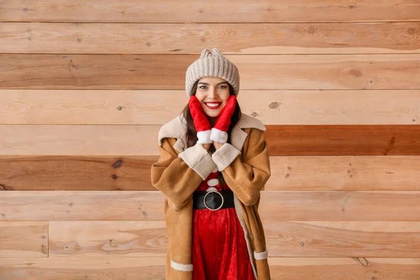 Krásná mladá žena v kostýmu Santa Claus proti dřevěné zdi — Stock fotografie