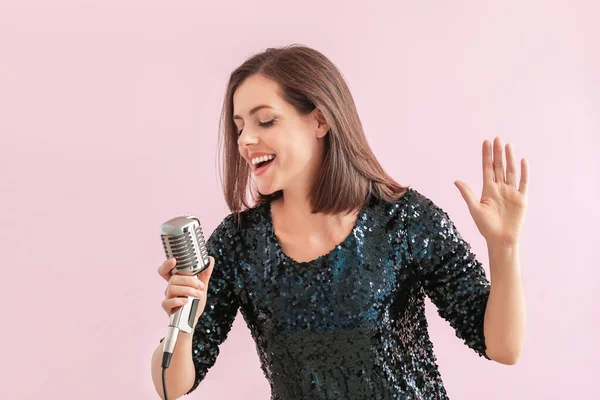 Linda jovem cantora com microfone no fundo de cor — Fotografia de Stock