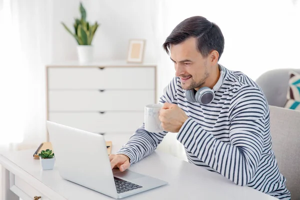 잘생긴 남자 집에서 노트북에서 작업 하는 동안 마시는 커피 — 스톡 사진