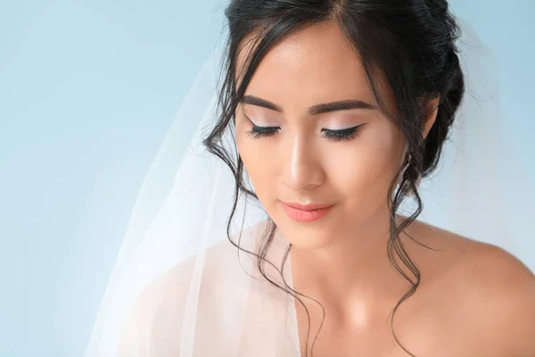 Beautiful young Asian bride on color background — Stock Photo, Image