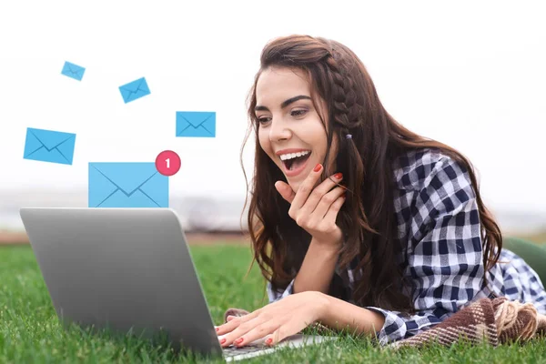 Jeune femme avec ordinateur portable vérifiant un e-mail en plein air — Photo