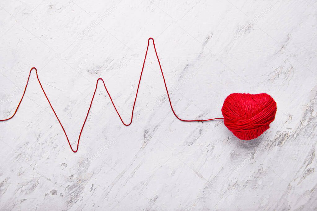 Composition with heart and cardiogram made of thread on light background