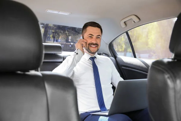 Успешный бизнесмен разговаривает по телефону в современном автомобиле — стоковое фото