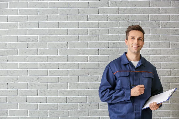 Male car mechanic with clipboard near brick wall — Stock Photo, Image