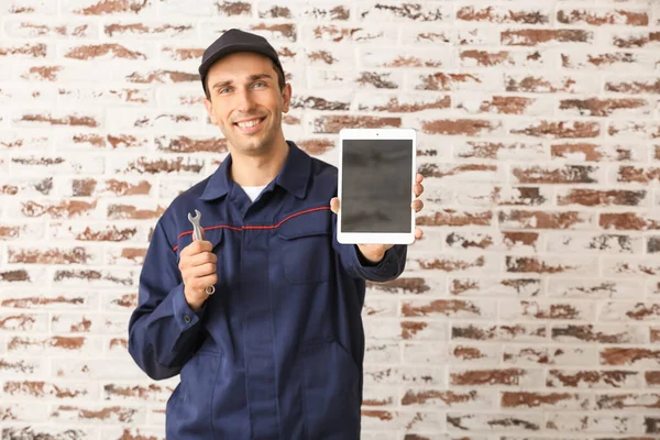 Male car mechanic with tablet computer near brick wall — Stock Photo, Image