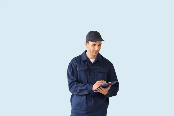 Male car mechanic with clipboard on color background — Stock Photo, Image