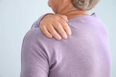 Arka planda omuz ağrısı çeken son sınıf öğrencisi kadın, yakın plan.