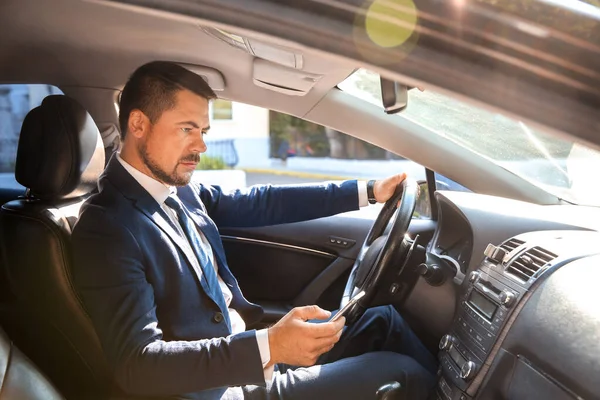 Successful businessman using mobile phone while driving modern car — Stock Photo, Image