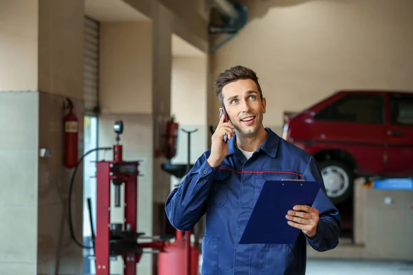 Male mechanic talking by phone in car service center — Stock Photo, Image