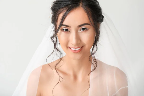 Beautiful young Asian bride on light background — Stock Photo, Image