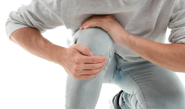Молодий чоловік, який страждає від болю в коліні на білому тлі, крупним планом — стокове фото