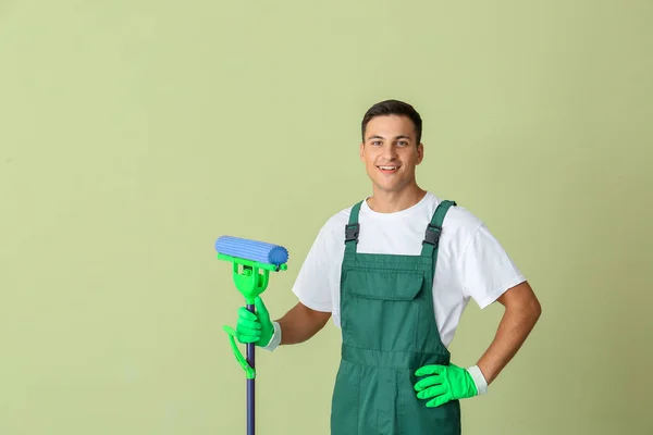 Young man with mop on color background — Stock Photo, Image