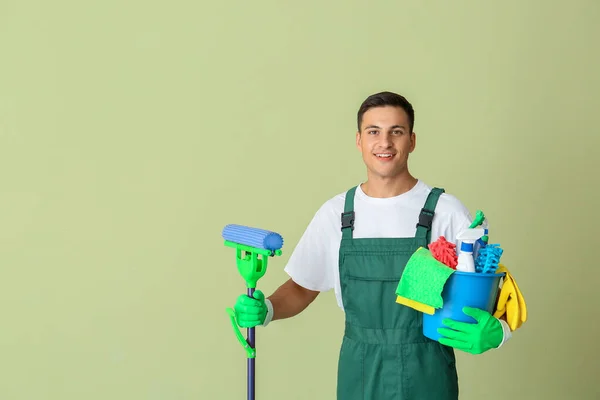 Young man with cleaning supplies on color background — Stock Photo, Image