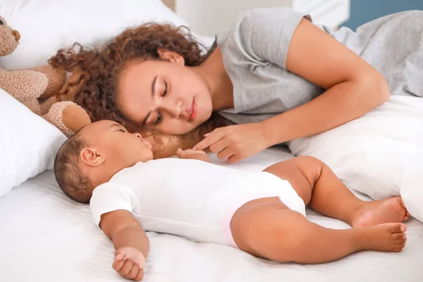 Joven mujer afroamericana y su bebé durmiendo en la cama — Foto de Stock