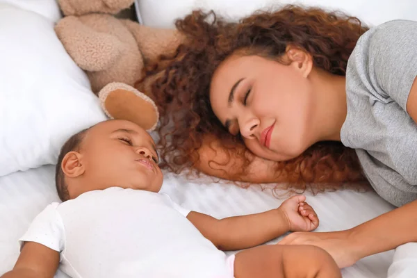 Young African-American woman and her baby sleeping on bed — Stock Photo, Image