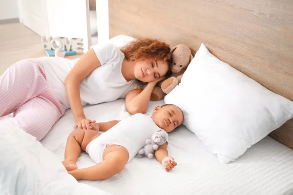 Young African-American woman and her baby sleeping on bed — Stock Photo, Image