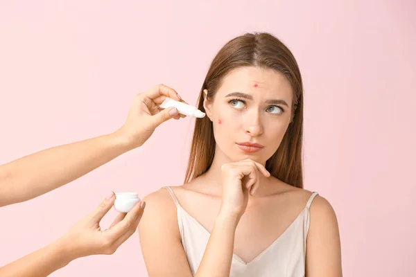 Retrato de mujer joven con problema de acné y manos con remedio sobre fondo de color — Foto de Stock