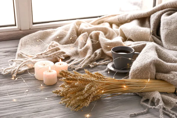 Рождественские огни, горящие свечи, чашка чая и клетка на подоконнике — стоковое фото
