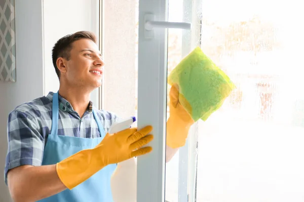 Fiatal férfi takarít ablakot otthon — Stock Fotó