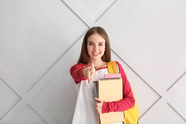 Female student pointing at viewer on light background — Stock Photo, Image