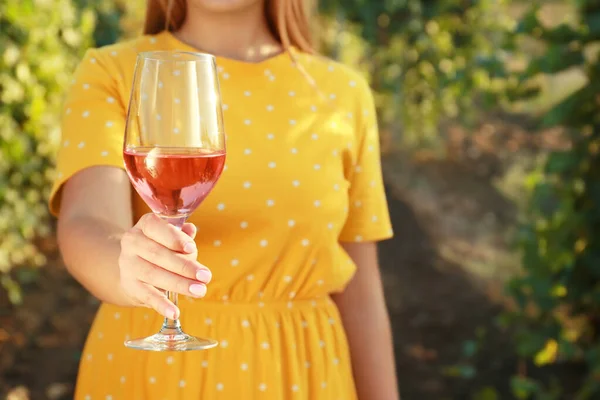 Mujer joven con copa de vino sabroso en el viñedo — Foto de Stock