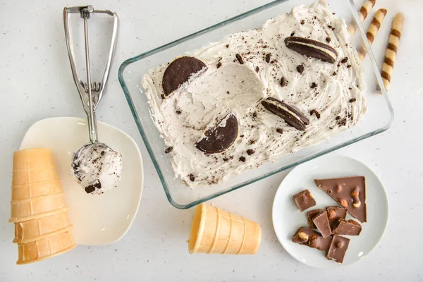 Sorvete saboroso com xícaras de wafer, biscoitos e chocolate no fundo branco — Fotografia de Stock