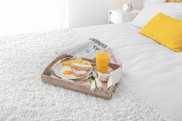 Tray with tasty breakfast and newspapers on bed — Stock Photo, Image
