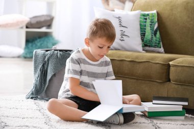 Evde kitap okuyan şirin bir çocuk.