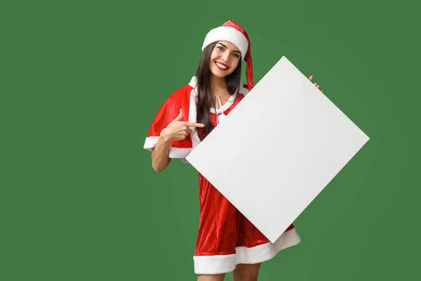 Beautiful young woman in Santa Claus costume and with blank poster on color background — Stock Photo, Image