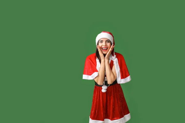 Mujer joven sorprendida en traje de Santa Claus sobre fondo de color —  Fotos de Stock