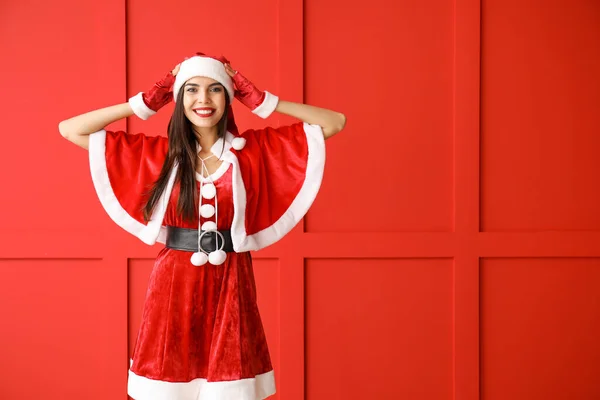 Bella giovane donna in costume da Babbo Natale contro la parete di colore — Foto Stock
