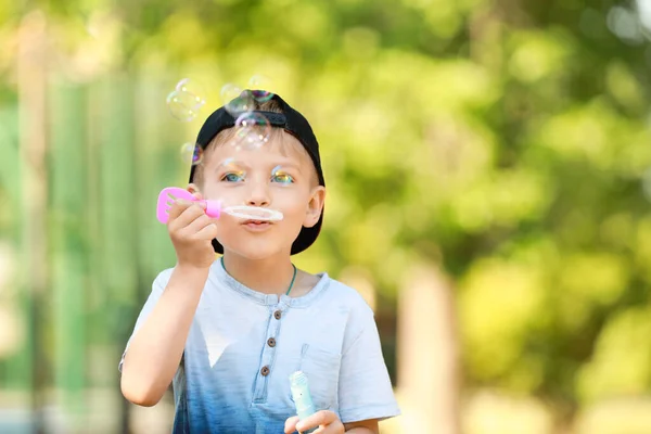 Söt liten pojke blåser såpbubblor i park — Stockfoto