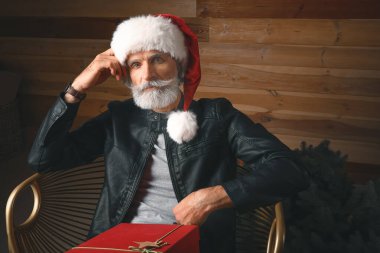 Noel hediyeli şık Noel Baba 'nın portresi. Kapalı koltukta oturuyor.