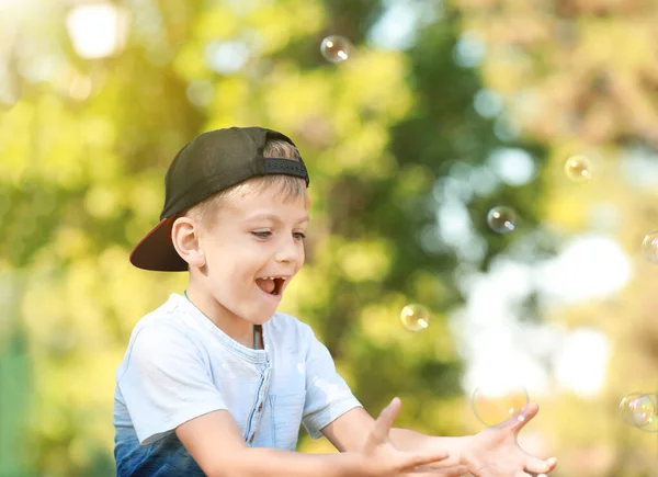 Söt liten pojke leker med såpbubblor i parken — Stockfoto