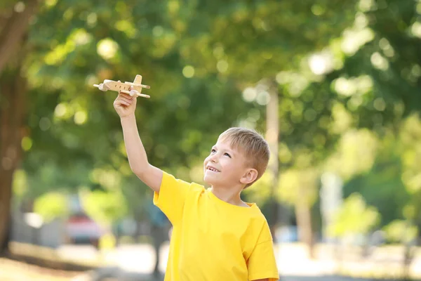 Söt liten pojke leker med trä flygplan i parken — Stockfoto