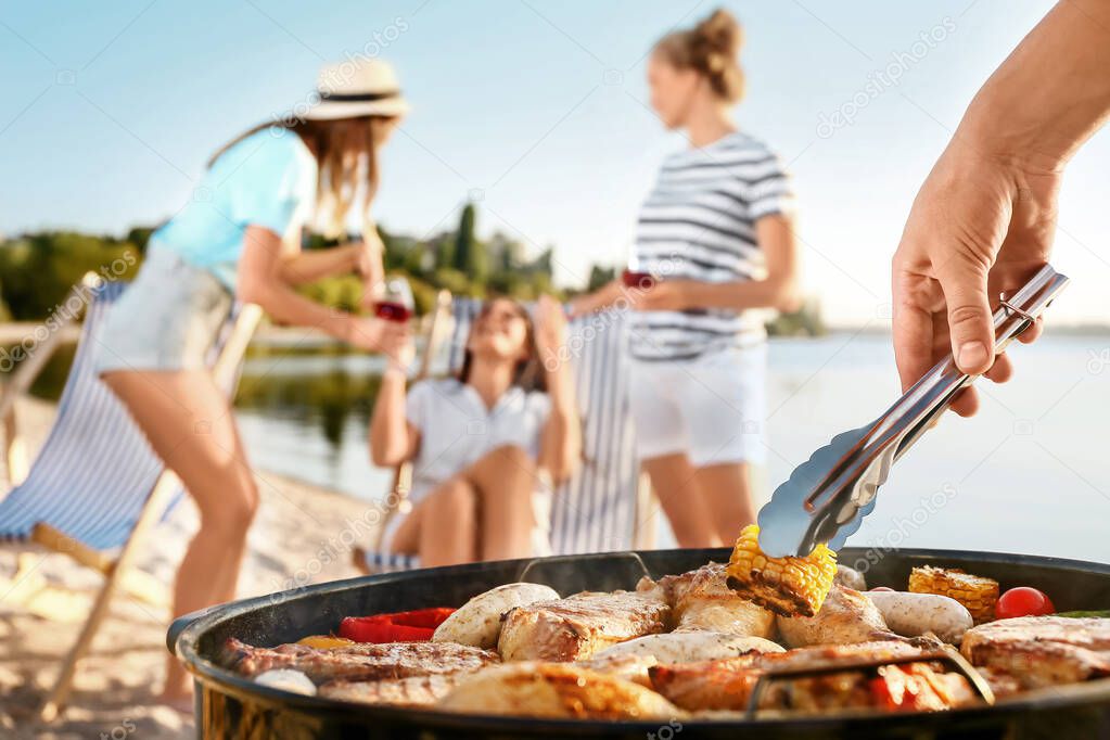 Man cooking tasty food on barbecue grill outdoors, closeup