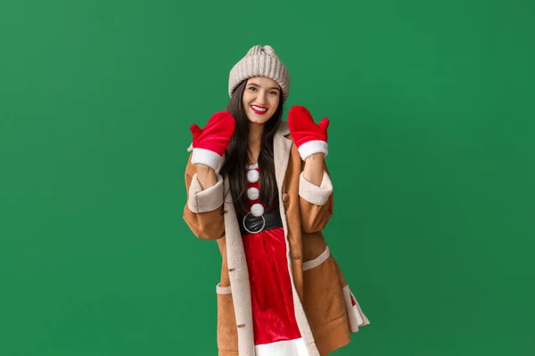 Beautiful young woman in Santa Claus costume on color background — Stock Photo, Image