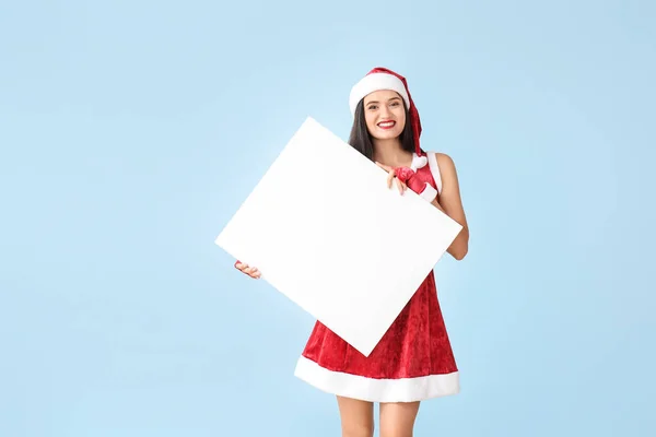 Mulher bonita em traje de Papai Noel e com cartaz em branco no fundo de luz — Fotografia de Stock